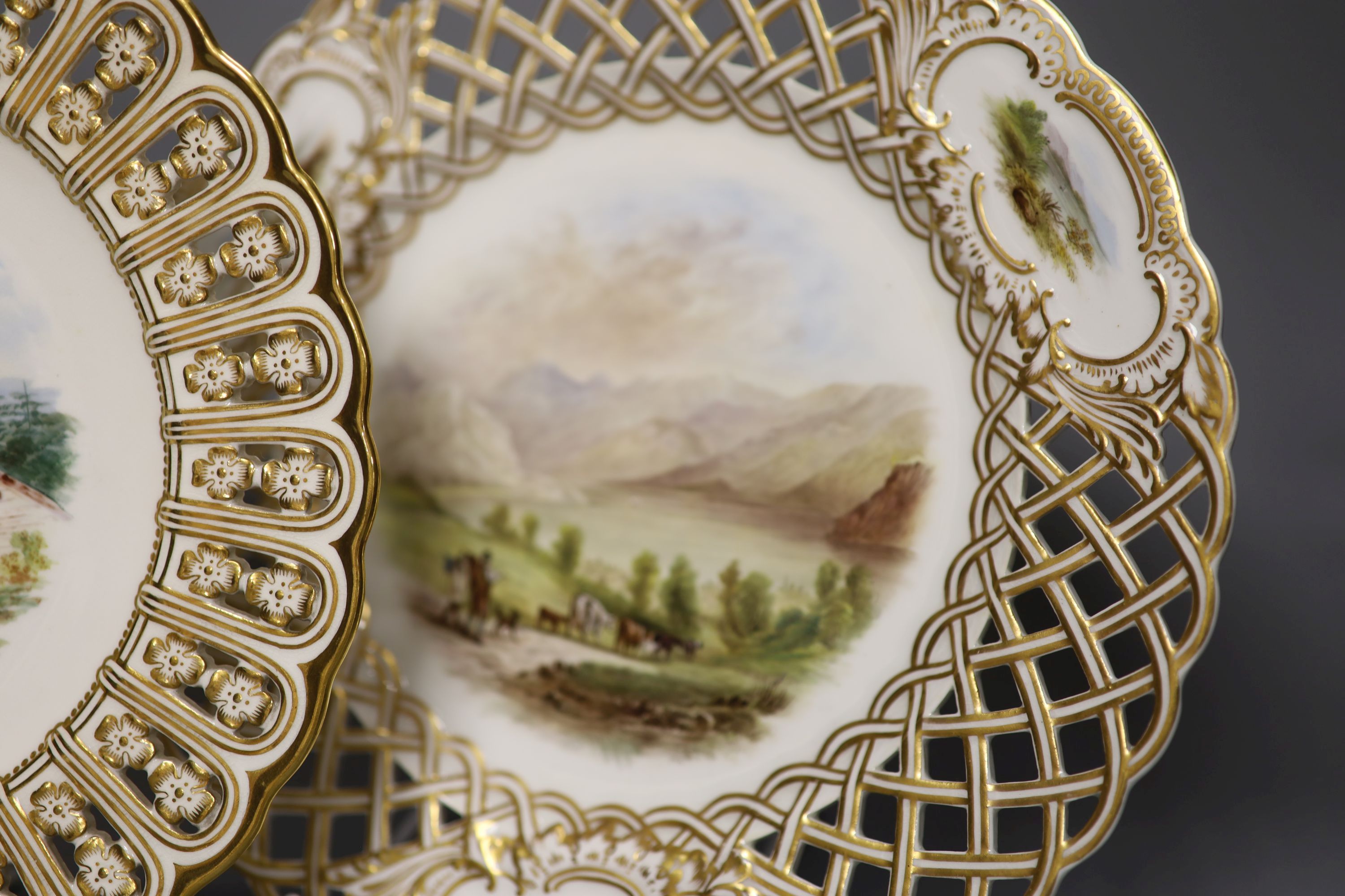 A pair of 19th century Minton pierced plates painted with landscapes, impressed marks, diameter 23cm, and a lattice work pierced plate